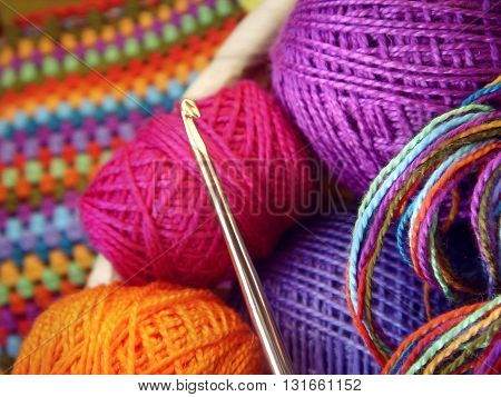 Crochet hook with a ball of colored yarn and knitwear