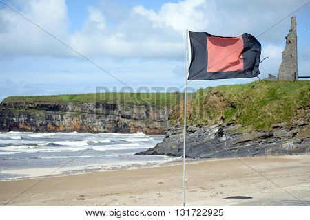 quicksilver flag flying beside surf school with ballybunion castle in background