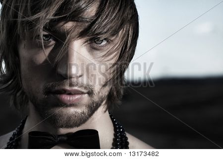 时尚拍摄的英俊青年构成的高顶礼帽和领结裸照在美丽的风景。