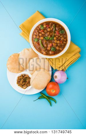 spicy chick peas also known as Chola Masala or Chana Masala or Chole served with fried puri, pickle and green salad