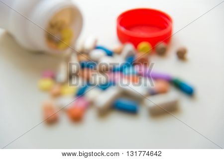 Blur of various medicine pills on white table.