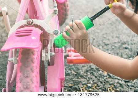 Selective focus on kid's hand acting like using air pumping inflate her bicycle tire - kid's play kid's imagination