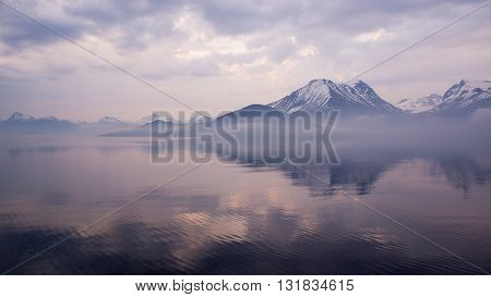 View of the mountains on the horizon in the Norwegian Coastline, misty and calm, early morning.