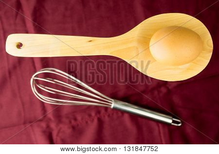 wooden spoon metal whisk and egg for a minimalist composition
