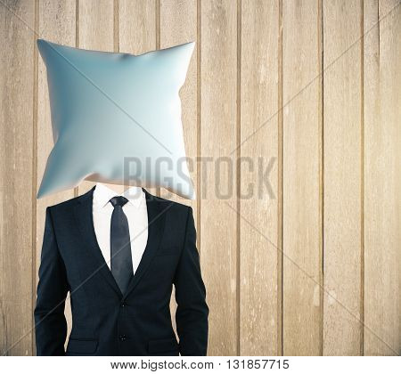 Pillow headed businessman on wooden plank background. Mock up