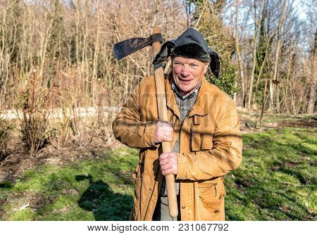 Senior Man With Ax Over His Shoulder In The Autumn Garden.