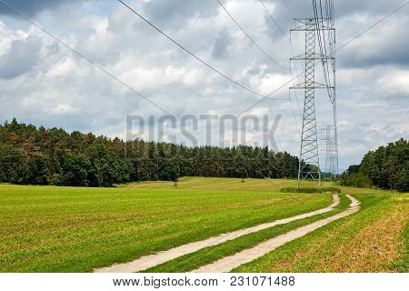 Transmission Towers With High-voltage Lines Passing Over A Meadow Near Forest Between Hrdlorezy And 
