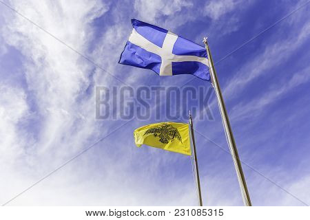 Greek And Byzantine Flags Waving On The Air Against Cloudy Sky