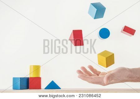 Male Hand Juggling Colorful Wooden Shapes. Concept Of Creative, Logical Thinking. Floating Shapes.