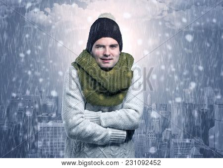 Young man freezing in warm clothing with city concept