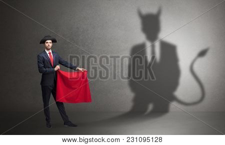 Businessman standing with red cloth in his hand and devil shadow on the background