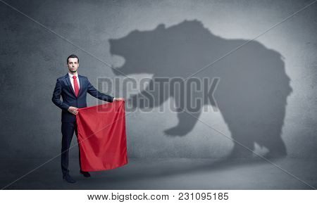 Businessman standing with red cloth in his hand and big bear shadow on his background