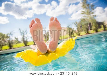 Beautiful sexy female feet relaxing while floating in a swimming pool.