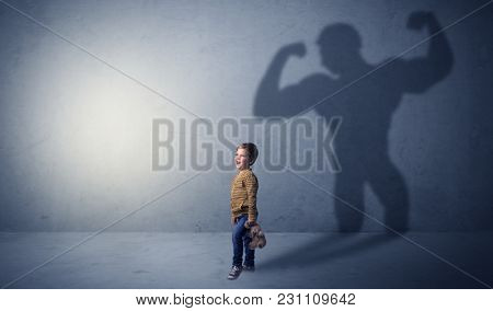 Little waggish boy in an empty room with musclemen shadow behind