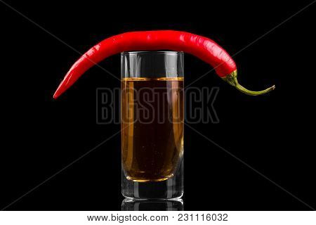 Glass With Alcohol, Top Pod Of Bitter Chili Peppers, Isolated On Black Background