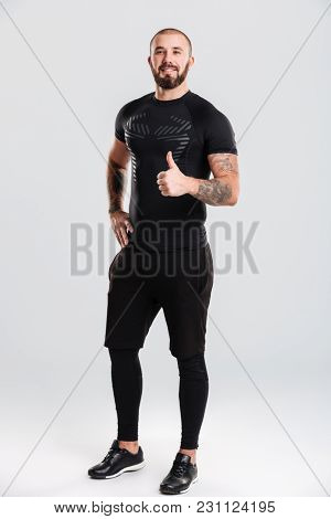 Photo of strong healthy cheerful young sportsman bodybuilder showing thumbs up. Looking camera.