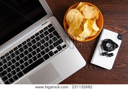 Workspace With Laptop, Flash-player And Bowl Of Chips On Wood Table. Bad Habits Concept