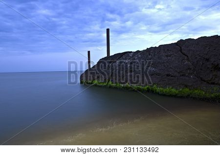 Concrete Breakwater In The Water On The Azov Sea Beach Shot In The Evening.
