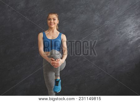 Young Woman Warming Up Before Training At Gym. Slim Girl Makes Aerobics Exercise At Gray Background 
