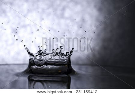 Splash Of Water In The Form Of A Crown On A Gray Background In Dark Tones With Splashes.