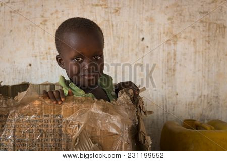 Nhacra, Republic Of Guinea-bissau - January 28, 2018: Portrait Of A Young Boy Playing In A Card Box 