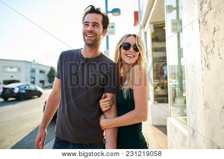 flirty couple having fun walking together down street