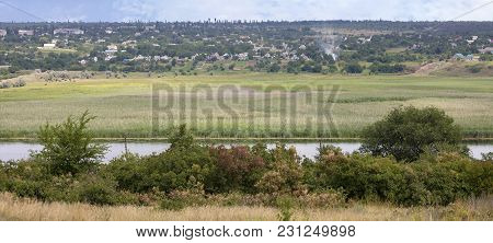 Scenic View From The Opposite Bank Of The River To A Village, Which Is Located Along The River With 