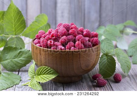 Red Fresh Raspberries On Brown Rustic Wood Background. Bowl With Natural Ripe Organic Berries With G