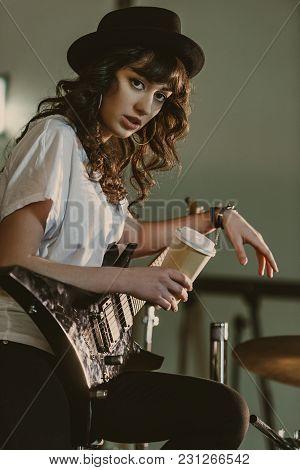Beautiful Female Musician With Electric Guitar And Cup Of Coffee To Go Looking At Camera