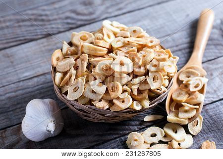 Bowl With Dried Garlic Flakes On Wooden Table