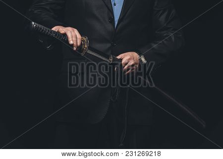 Cropped Shot Of Man In Suit Taking Out His Katana Sword Isolated On Black