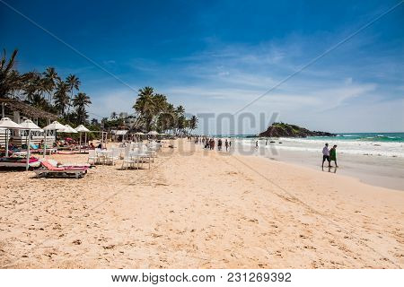 Mirissa Beach, Sri Lanka - JAN 2, 2017:  Tourists walking on the sand while enjoying the view across the wonderful beach of Mirissa on Jan 2, 2017. Sri Lanka.