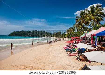 Mirissa Beach, Sri Lanka - JAN 2, 2017:  Tourists walking on the sand while enjoying the view across the wonderful beach of Mirissa on Jan 2, 2017. Sri Lanka.