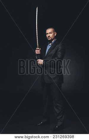 Serious Man In Suit With Japanese Katana Sword On Black