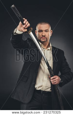 Man In Suit Taking Of His Katana Sword On Black