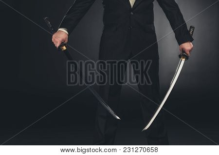 Cropped Shot Of Man In Suit With Dual Katana Swords On Dark Background