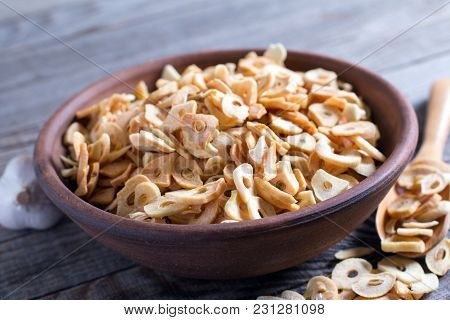 Bowl With Dried Garlic Flakes On Wooden Table