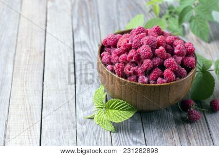 Sweet Raspberries In Bowl On Wooden Table. Close Up
