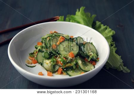 Chinese Cucumber Salad On The White Plate. Chopsticks. Asian Cuisine. Bell Pepper, Cucumber And Sesa