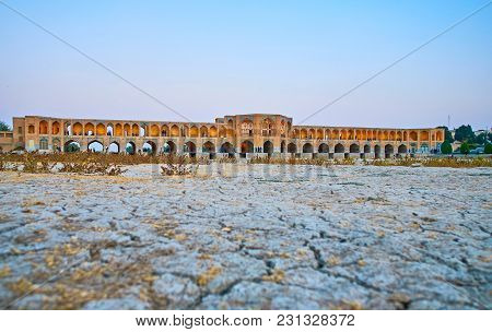 The View On Scenic Arched Khaju Bridge, Also Serving As Weir, With The Cracked Mud Of Dried-up Zayan