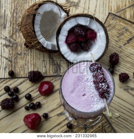Lilac Cocktail With Berries And Coconut On A Wooden Table