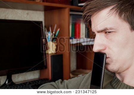 The Guy Sadly Looks Away, Closed The Rum With A Black Smartphone, In The Workplace