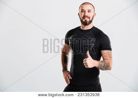 Photo of strong healthy cheerful young sportsman bodybuilder showing thumbs up. Looking camera.