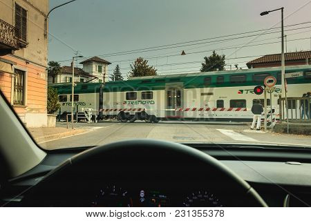 Driver Watches The Passage Of A Train Behind The Gates Of A Railroad Crossing