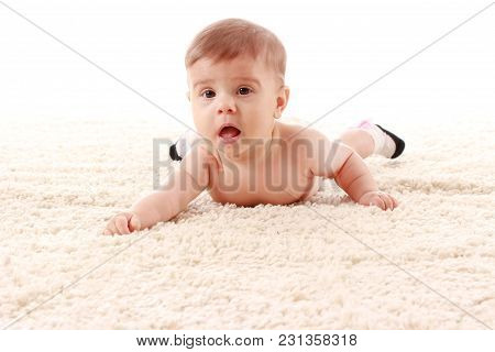 The Baby Is Lying On Her Stomach On The Carpet In The Room And Smiling On White Background