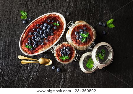 Tiramisu, Traditional Italian Dessert. With Savoyardi Cookies And Coffee. On Black Stone Background.