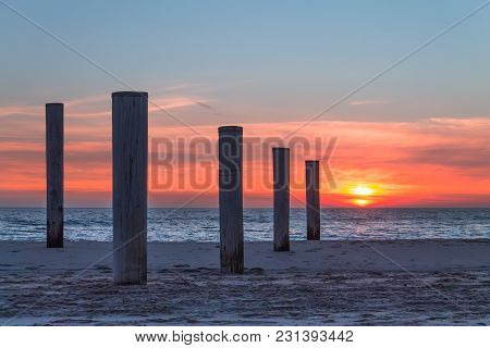Wooden Piles On An Empty Beach And A Beautiful Sunset Sky Over The Sea, Petten, Holland,north Sea