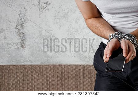 Close-up, The Man's Hand Is Tied With A Chain To The Smartphone. The Concept Is Dependent On Technol