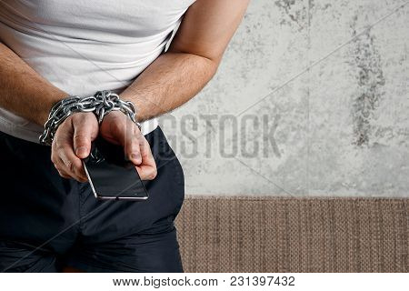 Close-up, The Man's Hand Is Tied With A Chain To The Smartphone. The Concept Is Dependent On Technol