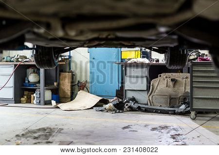 Car Hanged On Lift At Sevice Station. Dirty Vehicle  Maintenace Center. Disorder, Mud, Stains And Ch